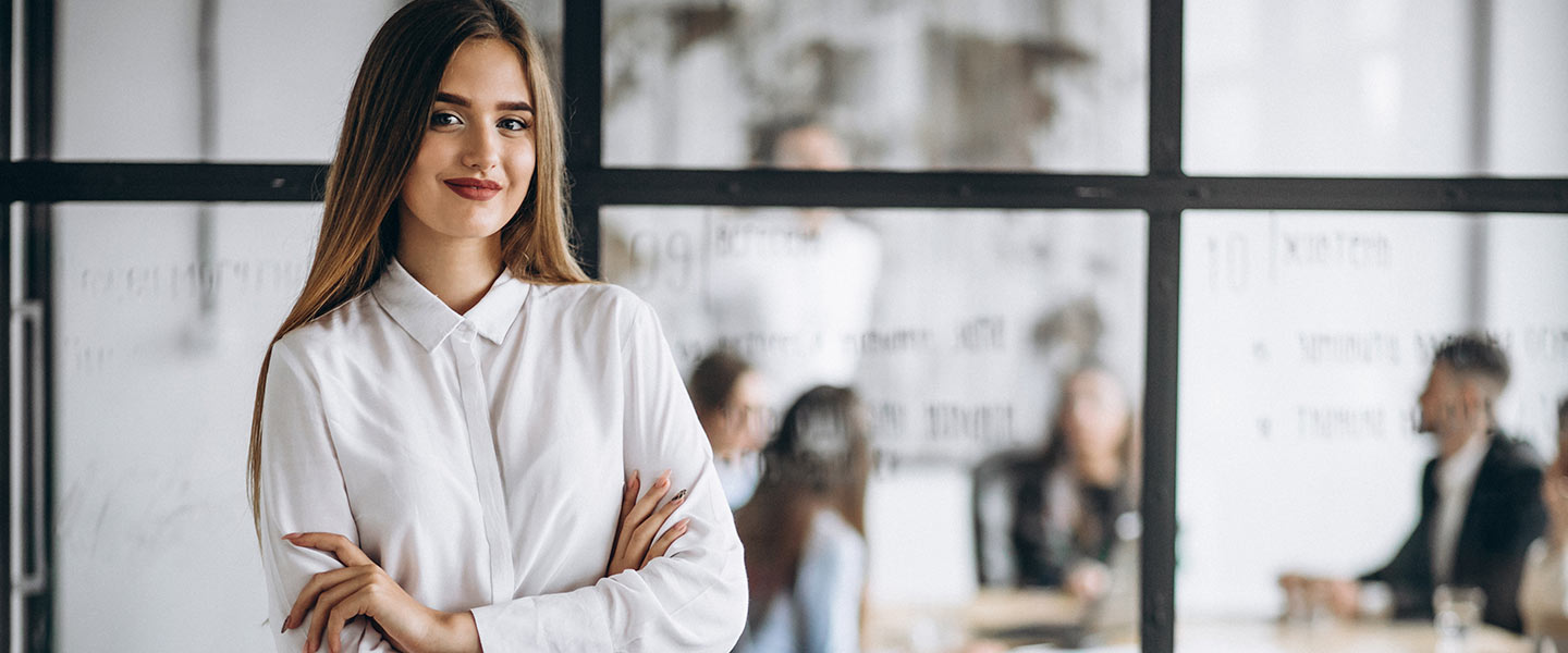 A Woman posing and smiling in a conference room background