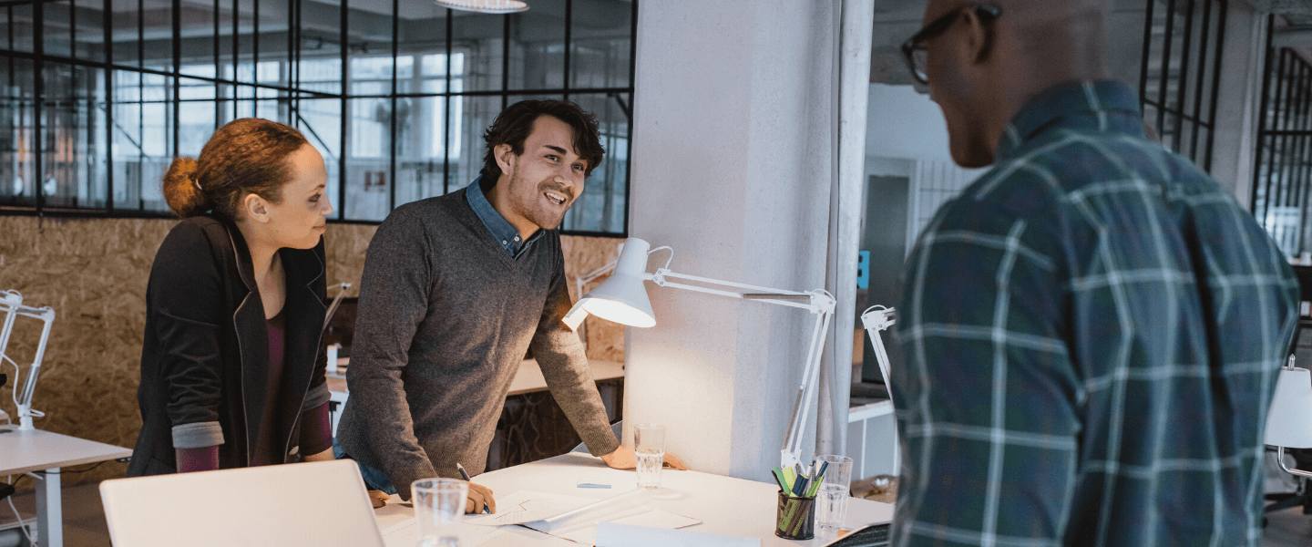 Three coworkers lean over a table at the office
