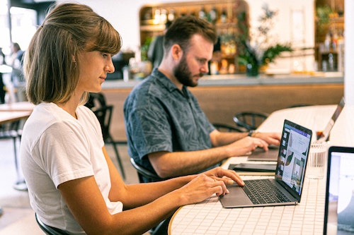 Man and woman working on laptop and typing