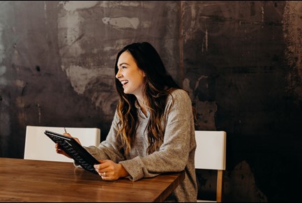 Woman smiling, using tablet, posing for photo