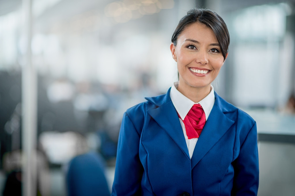 A flight attendant smiles for the camera in her uniform