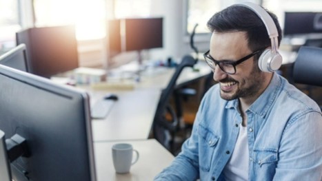Man typing, speaking to someone in headset, smiling and posing for photo