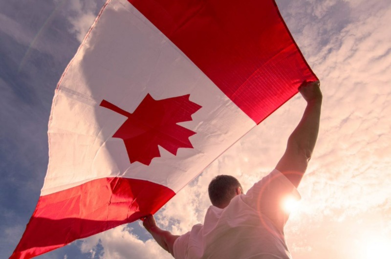 Man with Canadian flag at sunrise