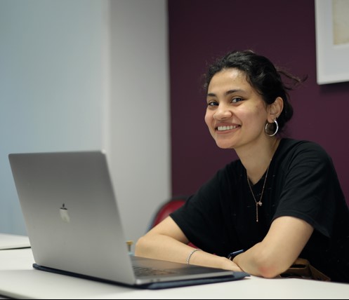 Woman smiling, hands folded, posing for photo