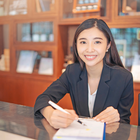 Woman smiling, writing with pen, posing for photo