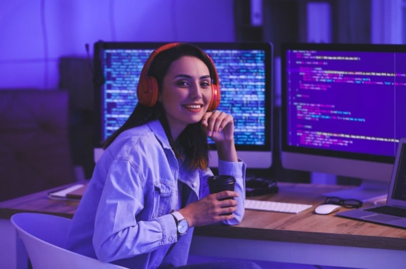 Woman with headphones and coffee cup, coding systems in background