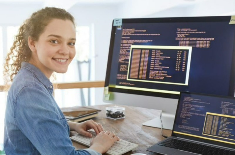 A woman smiling while typing on a keyboard, posing for a photo