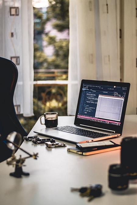 Laptop, mobile, mug, book and pen on the table