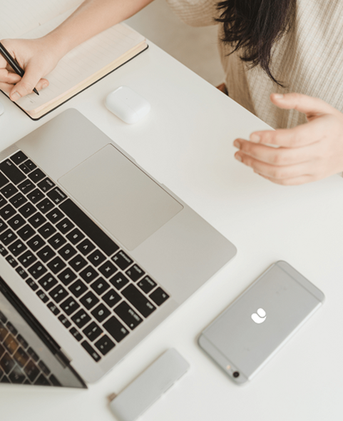 Woman noting in the book with pen by looking into laptop