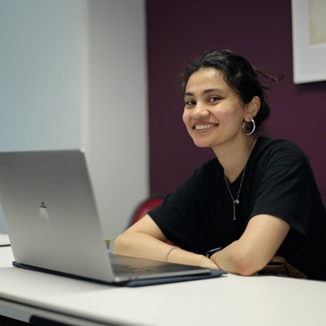 Woman smiling, hands folded, posing for photo