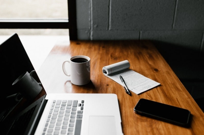 Table with laptop, phone, mug, book and pen