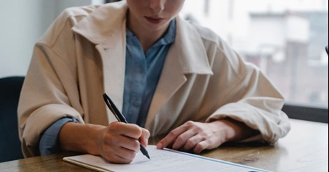 Woman writing with pen, posing for photo
