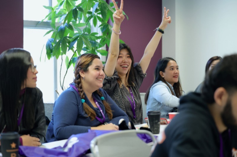 Woman smiling showing victory by hands raising, posing for photo