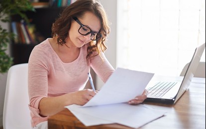 Woman marking with pen, wearing glasses, posing for photo