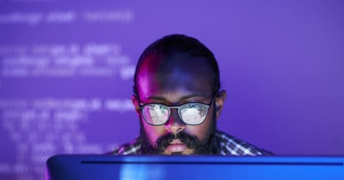Man typing, wearing glasses, posing for photo