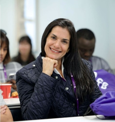 Woman smiling, hands folded, posing for photo