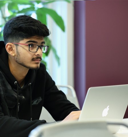 Man typing, wearing glasses, posing for photo