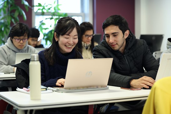 Woman smiling, typing, man watching the screen, posing for photo