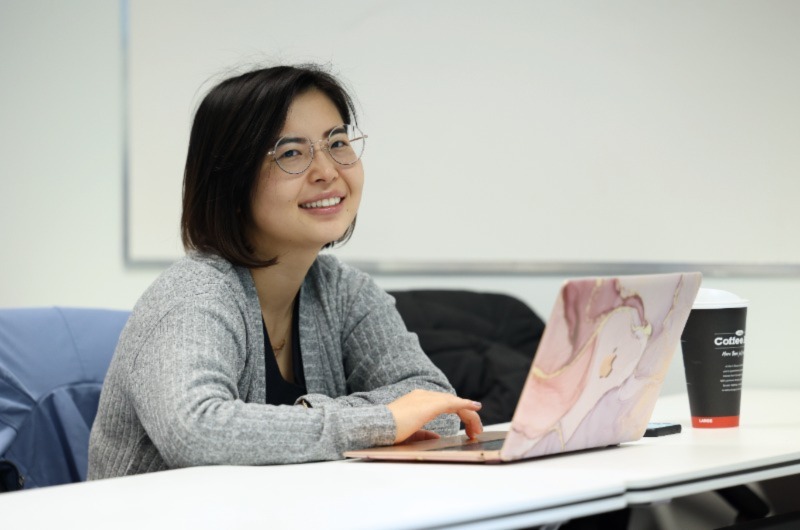 Student smiling while typing and posing for photo