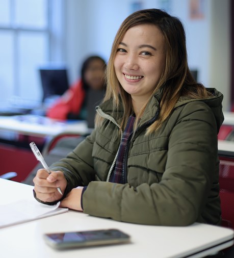 
Woman smiling, holding pen, posing for photo