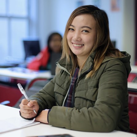 Woman smiling, holding pen, posing for photo