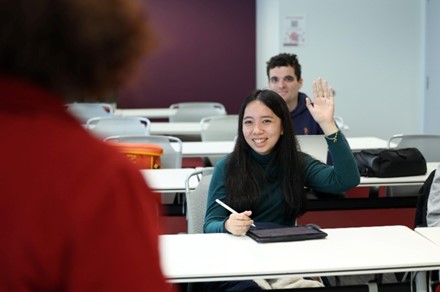 Woman smiling, raising hand, posing for photo