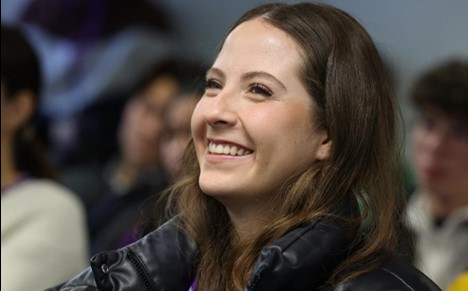 Woman smiling, hands folded, posing for photo