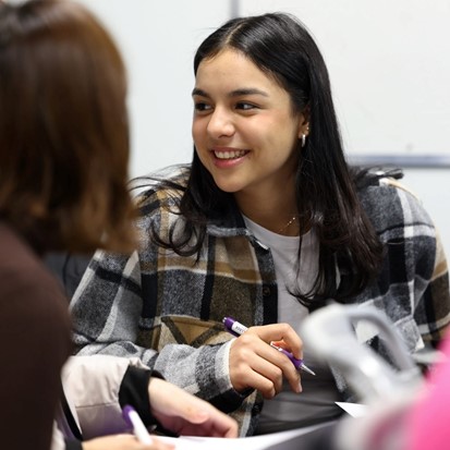 Woman smiling, holding a pen, posing for photo