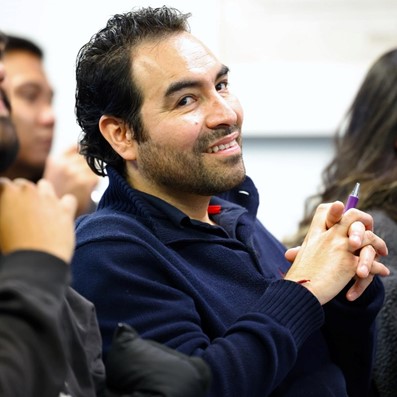 Man smiling, holding pen, posing for photo
