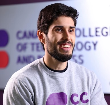 Man smiling, hands folded, posing for photo