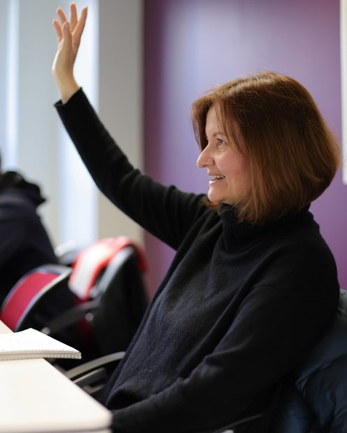 Woman smiling, raising hand, posing for photo