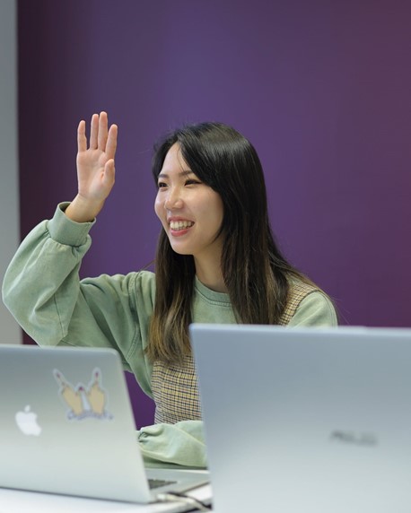 Woman smiling, raising hand, posing for photo
