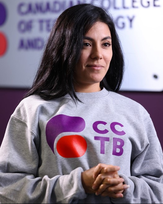 Woman smiling, hands folded, posing for photo