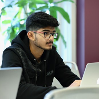 Man typing, wearing glasses, posing for photo
