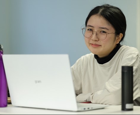 Woman typing, wearing glasses, posing for photo
