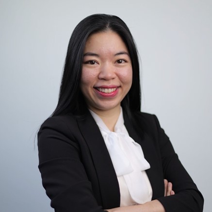 Woman smiling, hands folded, posing for photo