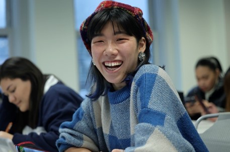 Woman smiling, hands folded, posing for photograph