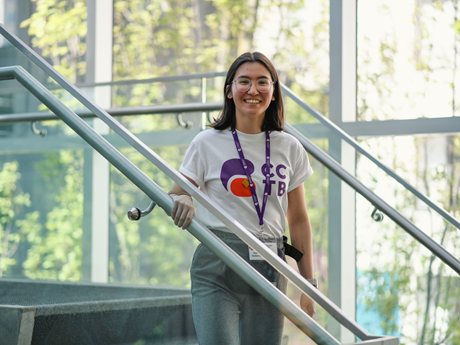 Woman smiling, standing on stairs, posing for a photograph