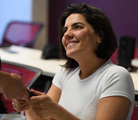Woman smiling, receiving the mobile from other, posing for photo