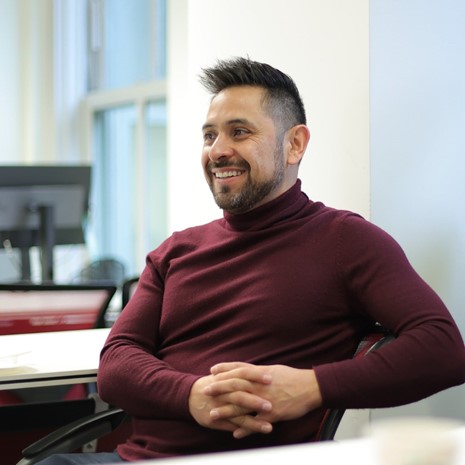 Man smiling, hands folded, posing for a photograph