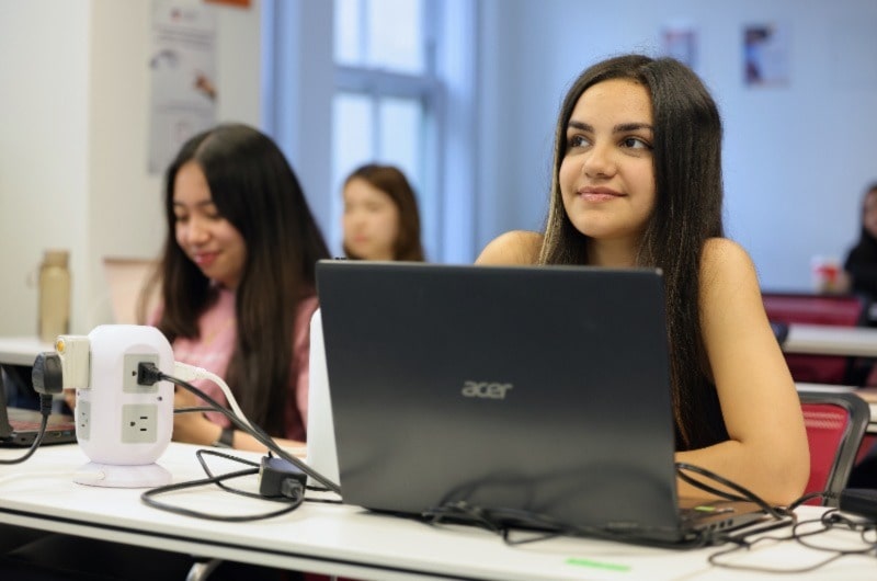 Woman smiling, hands folded, posing for photo