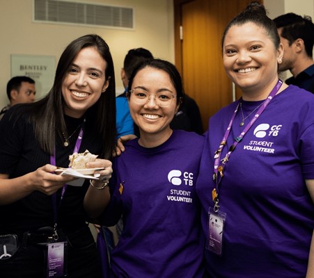 Three women smiling, weaing ID card, posing for a photograph