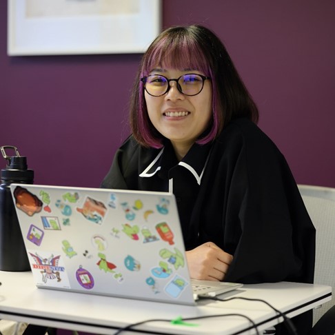 Woman smiling, hands folded, wearing glasses, posing for photo