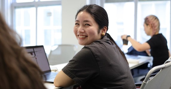 Woman smiling, hands folded, posing for a photograph