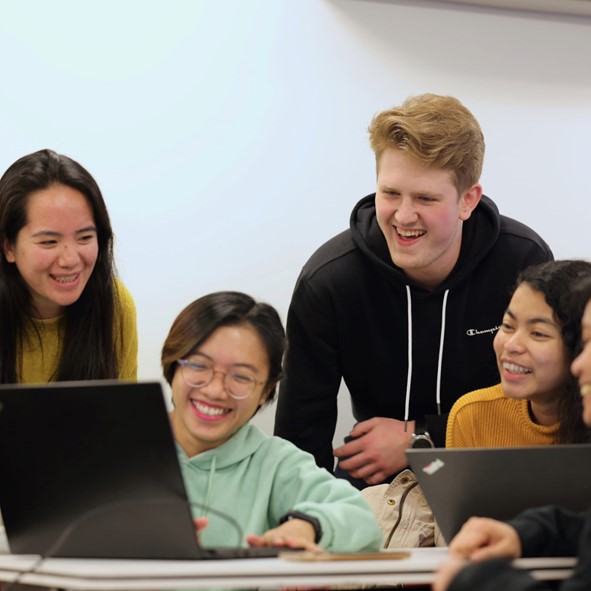 Group of people smiling, typing, posing for photo